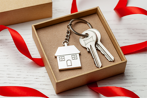 Why You Shouldn’t Rule Out Home Buying This Holiday Season - Christmas box with red ribbon containing a silver house key chain and two keys.